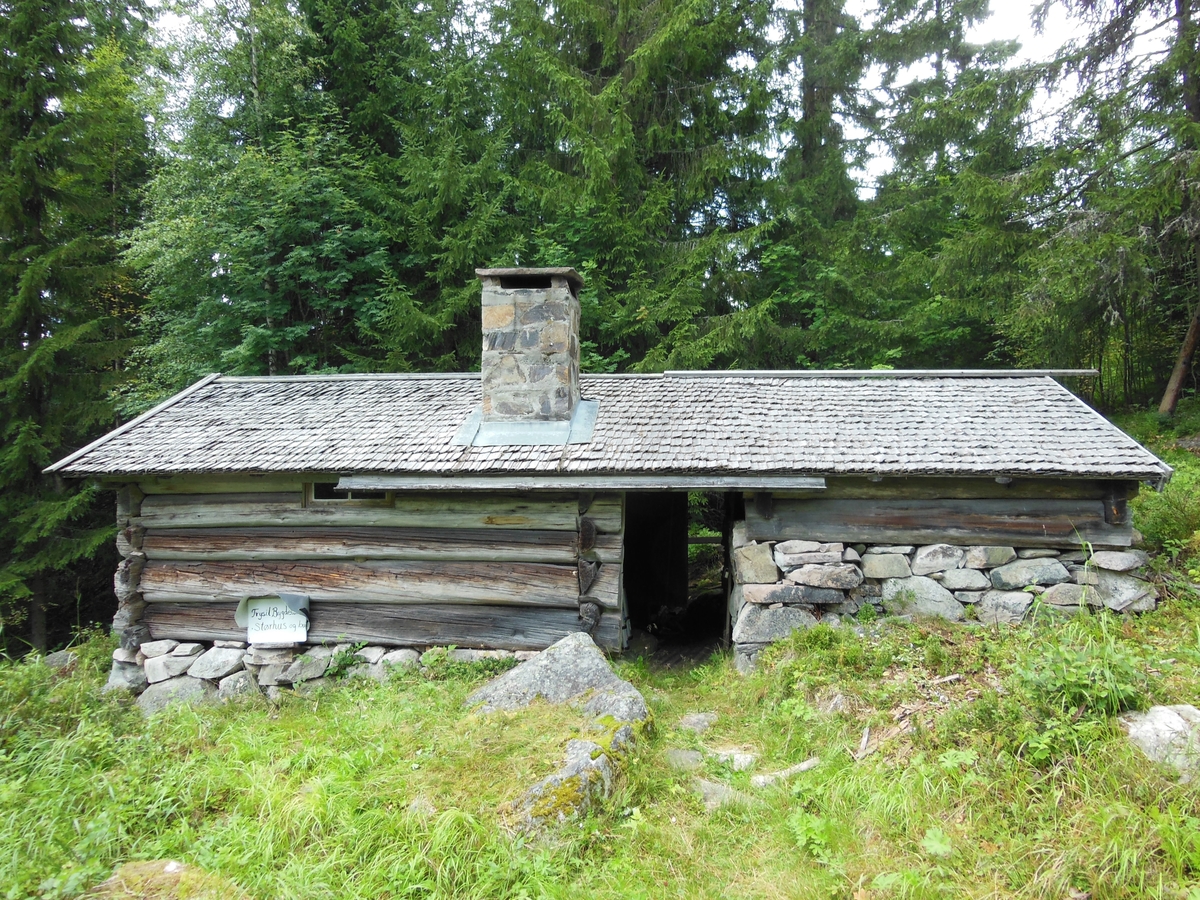 Størhuset er tømret av grove, kløvde stokker og har inngang i gavlen mot steinbua som er røstet under samme tak. Størhuset har mur (peis) med pannvinne.