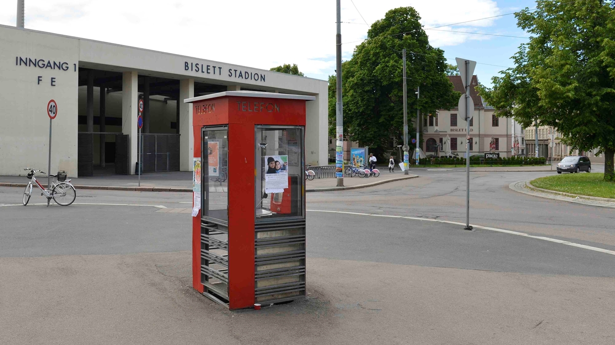 This is the story of how Norway’s most important conversation-space was designed by a young, freshly graduated man from Bergen.

“Norwegian architects are hereby invited…”
In the autumn of 1932, Oslo Telefonanlegginitiated an architectural competition. Finally, Oslo would get its own telephone booth. The city had had so called “talking-stations” from 1885, which in turn were overtaken by automatic telephones 
 only available at selected Narvesen kiosks. The state 
was of the opinion that now was the time to offer the public a better service; public telephone booths open 24/7, like the ones they already had in Sweden and England. But what would they look like, these new telephone booths? What considerations would it
 be necessary to take when designing it? The telegraph board developed a detailed list of demands and restraints: “The booth is intended to be placed outside on the streets and squares and need to be designed so that snow and ice does not hinder the opening and closing of the doors,” they wrote. “To prevent vandalism, theft, uncleanliness etc. inside the booth, it needs to be designed so that from all angles one may see what is going on in there.” Additionally, it would need to withstand storms and bad weather, and “preferably also being whipped by rain mixed with seawater” 

This was not all: The appearance would have to be «pleasing». The booth also needed to be movable, so that it could be taken in to be serviced at Telegrafverket’s main workshops. The reqired material was iron, and the surface was to be spray painted  preferably using car-body paint. There was a requirement for “a writing shelf, a pack shelf, and a suitable place for the telephone catalogue.” Also, there would need to be an illuminated TELEFON  sign, easily visible from all four angles. The total cost for each booth should not exceed 1000 kroner. The first prize for coming up with such a product was 800 kroner.

“Norwegianarchitects are hereby invited to partake in a competition for the design of a telephone booth…”  

The man with the solution
«At some point in 1932, Georg Fredrik sat at a party in Bergen. Maybe he felt a bit lost and forgotten as he often had throughout his life. He retreated to a quiet corner, took out a pencil and strted doodling on a matchbox.  According to my mother, this was how the telephone booth came into being.” In the book “Norges lille røde  historien om telefonkiosken,” Lars Fasting describes his father, the man who is far less known than the iconic architctural structure he left behind. Georg Fredrik Fasting was from Bergen, born into a family of working people and smallholders. One unusual facet of Georg Fredrik was that he was born without ears. His mother made sure he learnt to speak, read and write, 
ut Lars Fasting indicates that his father would seek refuge in drawing when the social challenges became too much to bear. And in the end drawing became his profession. In 1924 he secured a guarantor for a student loan, and started studying to become an a
rchitect at the NTH. Throughout the 1930s he entered several architectural competitions, with drafts produced, according to his son, “after work and in the late hours of the night.”

His efforts were not wasted. Out of 93 entries, with names such as “Flirt”, “Brrr”, “Ring” and “Amor”, the jury selected Fasting’s submission, “RIKS” as the new telephone booth: “The draft shows a strikingly simple solution to the task, technically as well as aesthetically well worked out.”

Taut and provident
Simple and aesthetc are the keywords here. Fasting had designed a booth pointing towards the future, and to modernism. Just how modern it was can be seen by comparing RIKS to the British telephone booth, also designed in the interwar-era. While the British version with it classicistic style is looking back to the heyday of the empire, Fasting’s booth is progressive and functionalistic. Like most Norwegian architects, Fasting broke with the classicistic style of architecture after the Stockholm-exhibition in 1930. “After it, almost all buildings erected in Norway until the German invasion in 1940, were in the functionalistic architectural style,” writes senior curator of architecture at the Norwegian National Museum, Ulf Grønvold, in the book, “Den lille røde”.“TheNorwegian booth is a piece of functionalistic architecture, an asymmetric composition with its roof slab overhanging the word TELEFON, in bold sans seraph lettering,”concludes Ulf Grønvold.

Fashionably red
And it was red. Fasting chose a colour which was part of the modern palette. “A bright red colour, but not as shiny as a signal red, the character of the colour places it among the fashionable colours within functionalism,” states paintings conservator and researcher in NIKU (Norwegian Institute for Cultural Heitage Research), Jon Brænne. In his opinion, Fasting went for visibility without making the booth stand out too much from its surroundings. The original colour was in use up to around 1950, when it changed to signal red. Towards the end of the 1970s the clour was again adjusted towards today’s orangey red.

The design, however, has not changed. RIKS is eighty years and still looks remarkably good. That’s what makes Fasting’s telephone booth a classic  even before it was added to DOCOMOMO’s list over moden icons of design. For Telenor, the telephone booth has served as a pathway into the hearts of the public. For many, Telenor (Televerket) was synonymous with exactly this telephone booth, because this was where one would go to place a call. Having a home
phone was not common until the 1980s. As such the red box became part of the Norwegian everyday and consciousness. The symbol- and publicity value of this is hard to evaluate, but in 2007 it was time to give honour where honour was due, Telenor, in consul
tation with the Directorate for Cultural Heritage, decided to preserve 100 telephone booths for all eternity.

And what about Georg Fredrik Fasting? What happened to him? At the age of 56 an entry in his diary states: «I CAN HEAR». As the first person in th world he had undergone an operation where he had ear canals constructed and eardrums fitted. For the rest of his life, the man behind Norway’s own telephone booth could answer the telephone himself.

Source: Norges lille røde historien om telefonkiosken (2007), issued by The Norwegian Telecom Museum and Telenor Cultural Heritage.