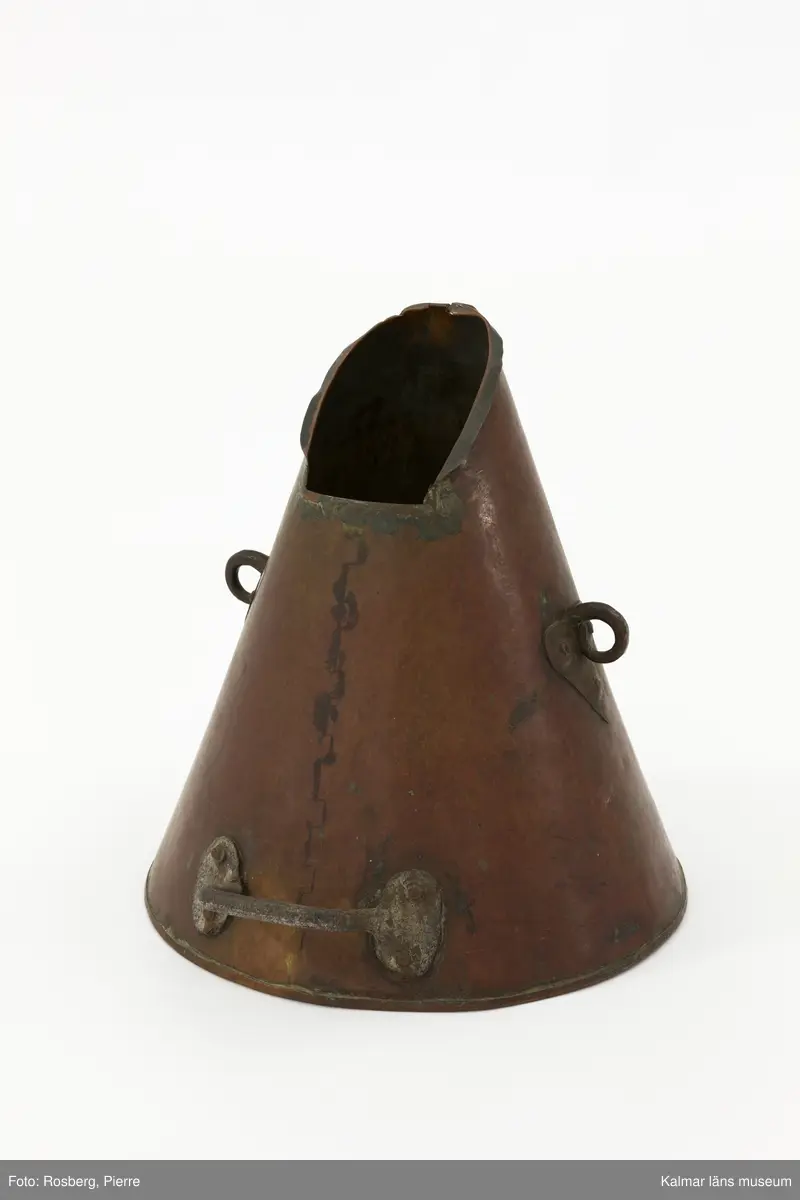 KLM 13315. Brännvinsmått, metall. Konformigt mått av koppar med handtag. Stämplar: Krona (kontrollstämpel) 4 34 5K LI W 1872 NEL 2879 PES 1880 1881 1882 1883 krona (kontrollstämpel) 14 85 86 87. Står i låda KLM 45504.