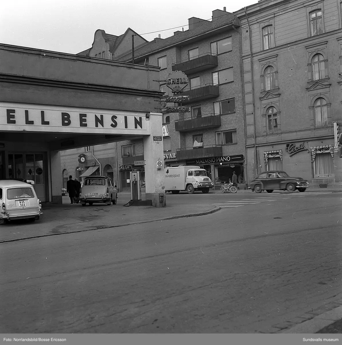 Gatuvyer i korsningen Köpmangatan-Nybrogatan med Shellmacken i hörnet, Cecil, Malmsjö piano med flera butiker.