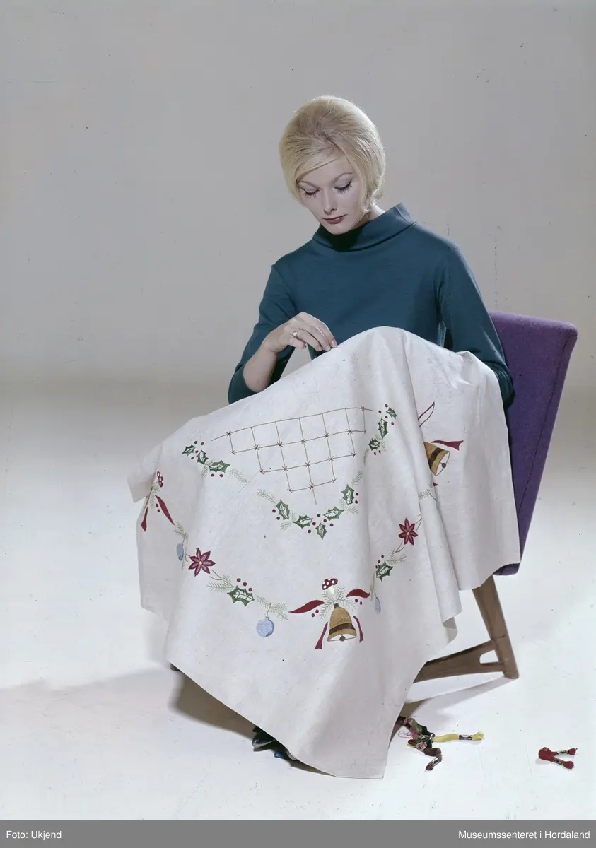 Reklamefoto av brodert juleduk, publisert i Norsk Ukeblad. Sydd med moulinegarn på lin.

"Ja, tiden går - og det er nok ikke noe for tidlig å begynne å sy juleduken nå, hvis den skal bli ferdig til jul.(...)"