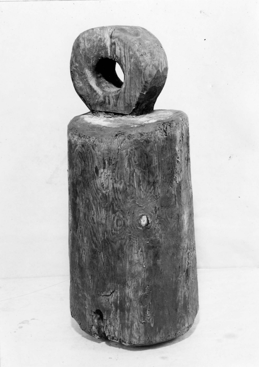 Cylindrisk, svagt konformig. Utthugget platt huvud med större hål för bojrep. På cylinderns nedre ände ett genomgående mindre hål med fastsittande gammalt tågvirke (surrningslina).