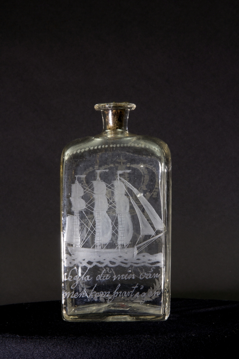 Längs flaskans övre kant en dekorativ bård av prickar. Gravyr på ena långsidan föreställande ett tremastat skepp med fulla segel. Gravyr på andra långsidan föreställande en sluten krona ovanför en lagerkrans som omsluter texten "Oscar Den 1ste". Blomstergirlanger på flaskans kortsidor.