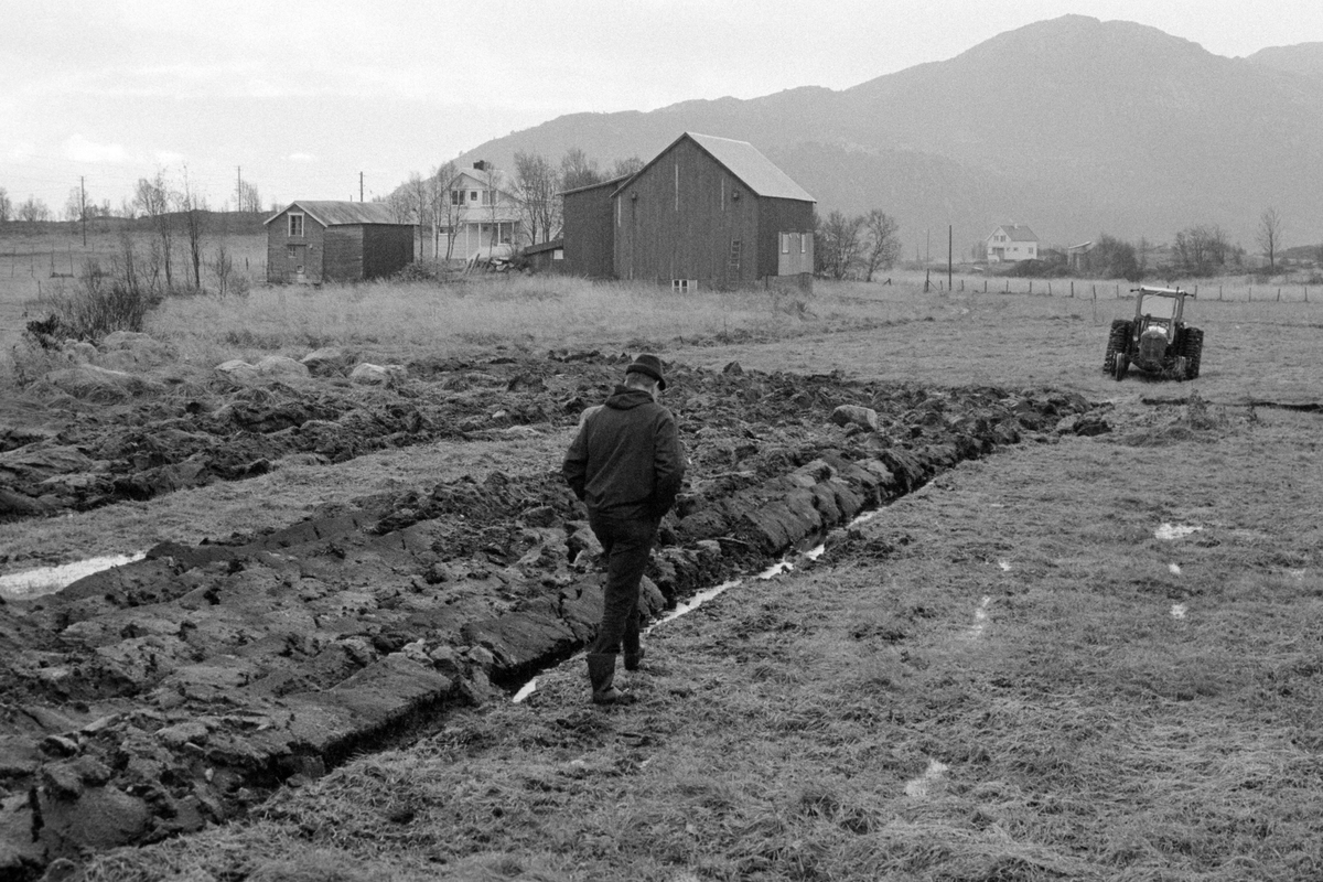 Nypløyd mark. Traktor og gårdsbygninger i bakgrunnen.