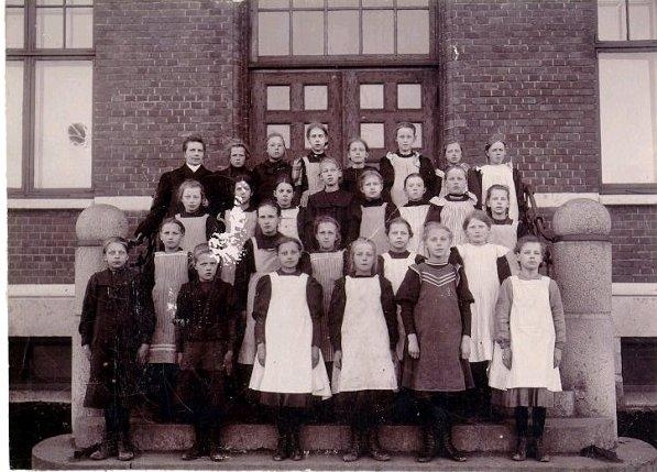 Folkskolan. Skolklass. Övre raden fr. vänster: 1. Folkskollärare Augusta Hallenius, 7. Ingeborg Johansson, 8. Harriet Fredriksson f. Bohlin. 2:a raden: 1. Ellen Jonsson, Wetterlinsgården, 4. Elsa Noring, slöjdlärare, 5. Ruth Andersson, bagare. 3:e raden: 4. Anna Eriksson (Norders Bokhandel), 5. Lilly Wennberg. 4:e raden = främre raden: 1. Märta Borg, 2. Ester Hjertman, 3. Elna Johansson, 4. Linnea Spångberg, 5. Jenny Leijon, 6. Elvira Sand.