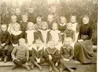 Lärarinnan fröken Maria Larson med en årsklass småskolebarn omkring 1900.