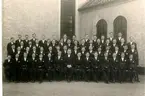 Konfirmander 1935. Sittande från vänster: I. Persson, Rolf Gannemark, K.A. Josefsson, Harry Friberg, Arne Jonsson, Rune Jonsson, Gillis Claesson, Prosten Fritz Wetterholm, Gösta Johansson, Björn Eriksson, Alf Johansson, Nisse Hall, Stig Johansson, Yngve Grehn, Bertil Liberg. Andra raden från vänster: K.E. Gustavsson, Rolf Johansson, Bengt Nilsson, Östen Johansson, Lundell, Stellan Melin, Åke Karlsson, okänd, okänd, Erik Jakobsson, Ingemar Törnkvist, H. Johansson, Olle Holgersson, Arnold Andersson. Tredje raden från vänster: Jan Wallin, Per Wallin, Karl-Erik Sandberg, Herbert Johansson, Tore Hindricks, Elmered - tidigare Johansson, Erik Grahn, John Andersson, Gunnar Svärd, Tage Isaksson, Karl-Erik Rytting, Gösta Oskarsson, K.E. Pettersson, Åke Dahlin, Rune Palmkvist, George Jansson. Övre raden från vänster: Valter Flobäck, Sven Frimansson, Valter Johansson, okänd, Lennart Andersson, Ingemar Lundahl, Sven Ljungström, Karl-Erik Josefssson, Karl-Erik Norén, Anders Heriberts, Rune Käll, Bengt Setterberg, Stig Karl