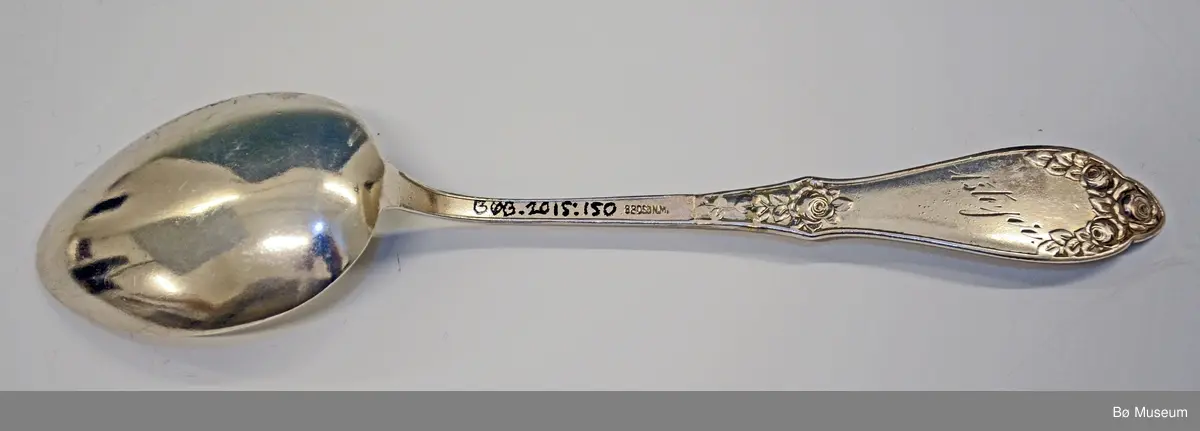 Spiseskje, sølv.
Gravert tekst: Gjentuns premie - bak: 1ste pr.
 
Stempel: 830 S ) NM (= Norsk Mønster).
Mønster: Opphøyet rose
