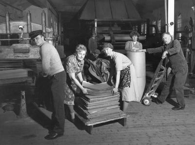 Kvinner som sorterer papir i fabrikken, såkalte papirhøner. Har på seg gamle klær med skaut og forkle.