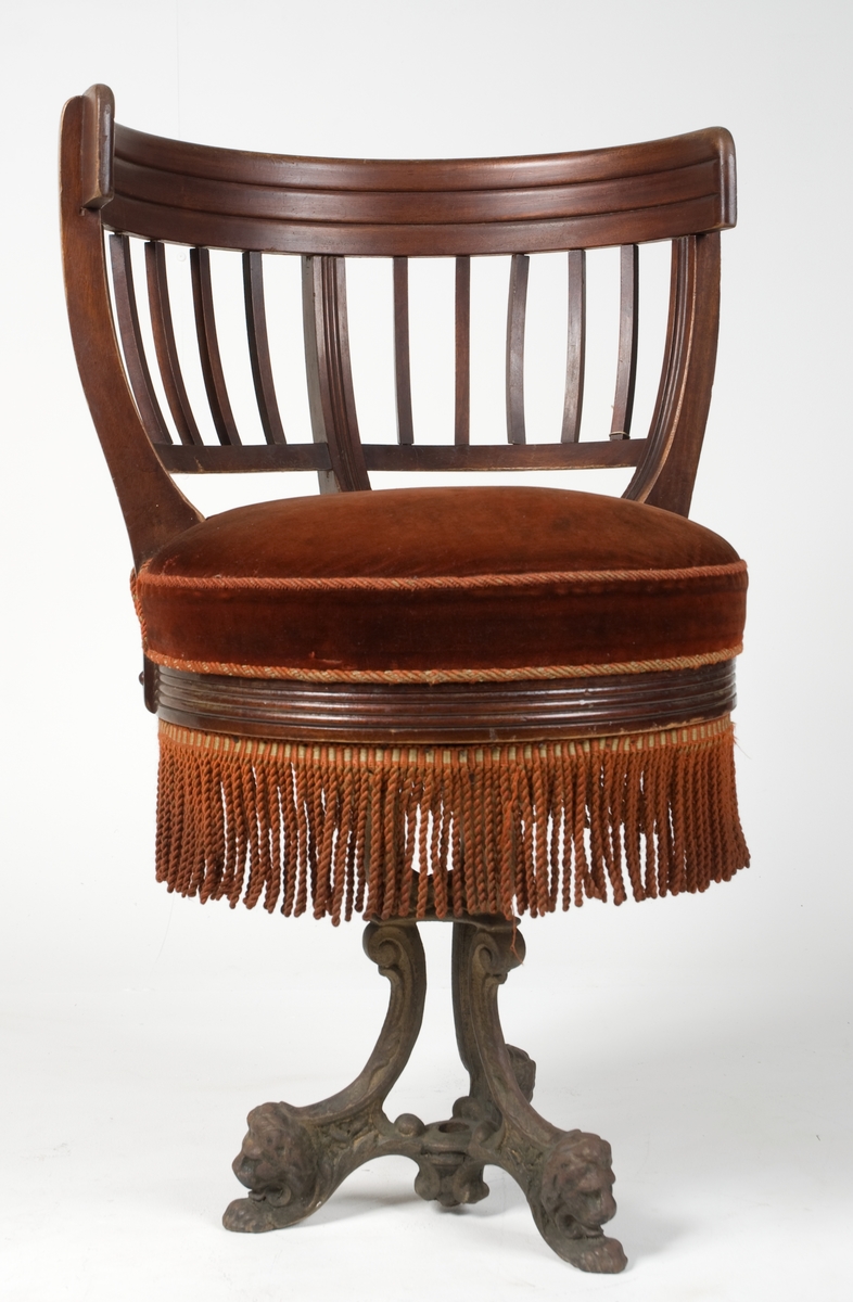 Stol av mahogny med halvcirkelformat ryggstöd (en av sex stycken likadana). Vridbar sits med resårer. Plyschklädda och försedda med fransar. Underrede av gjutjärn med tre fötter och en skruv i mutter för fastsättning i däck.