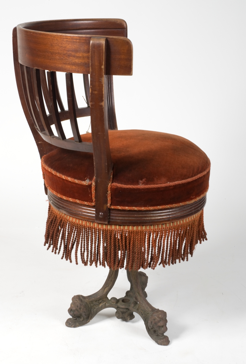 Stol av mahogny med halvcirkelformat ryggstöd (en av sex stycken likadana). Vridbar sits med resårer. Plyschklädda och försedda med fransar. Underrede av gjutjärn med tre fötter och en skruv i mutter för fastsättning i däck.