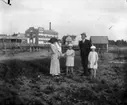 Grupp fem personer. Bostadshus och fabriksbyggnader i  bakgrunden.
Emilia Johansson med döttrarna Ingeborg, Brita och Hedvig. Mannen är Karls bror Olof Johansson.
Bilden tagen före mars 1915 då Hedvig dog.
Platsen Örebro ? Hallsberg?
Se även bild 16.