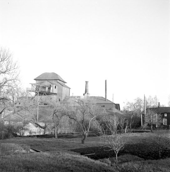 Pershyttan (Gamla Pershyttan) den 17 maj 1937. Hyttan i byn Pershyttan, vilken kallas "Pershytte hytta", är synlig i bakgrunden. Verksamheten (järnframställningen) är fortfarande i drift. (Den lades dock ner år 1953.) I förgrunden syns en välskött trädgård med några nyutslagna lövträd, vilka troligtvis (till största delen) är fruktträd.