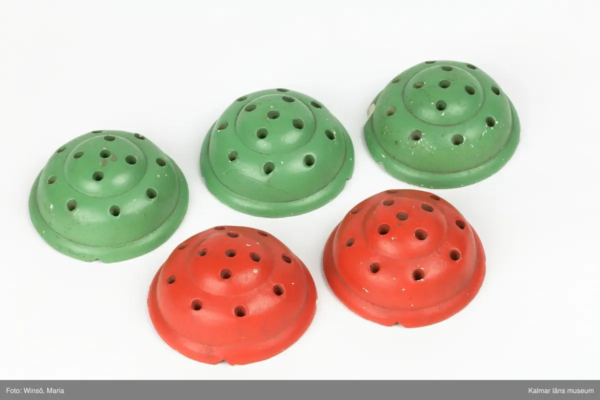 KLM 28228:8:1-5. Blomhållare, fem stycken. Av keramik. Rund, toppig form med 13 hål i vardera för placering av blommor. Två stycken är rödmålade och tre stycken gröna.