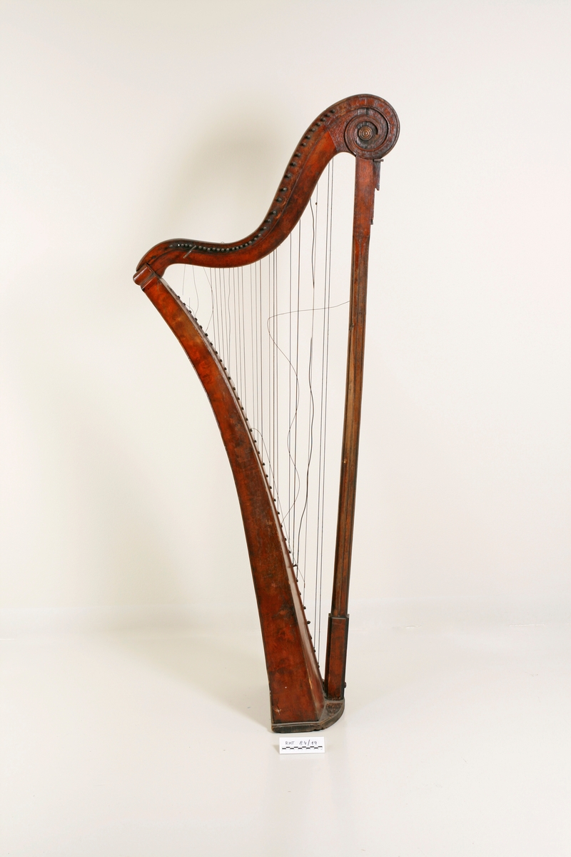 Hakeharpe, med hakemekanikk, i barokk stil. Rett forstang, kannelert søyle og buet kasse. Haker av jern. Innvendig forsterninger under lokket. 35 strenger; strengestol (Bredde, diskant: 15mm, bass: 31mm) dekorert på øvre avslutning. Ingen signatur eller produksjonsnummer.