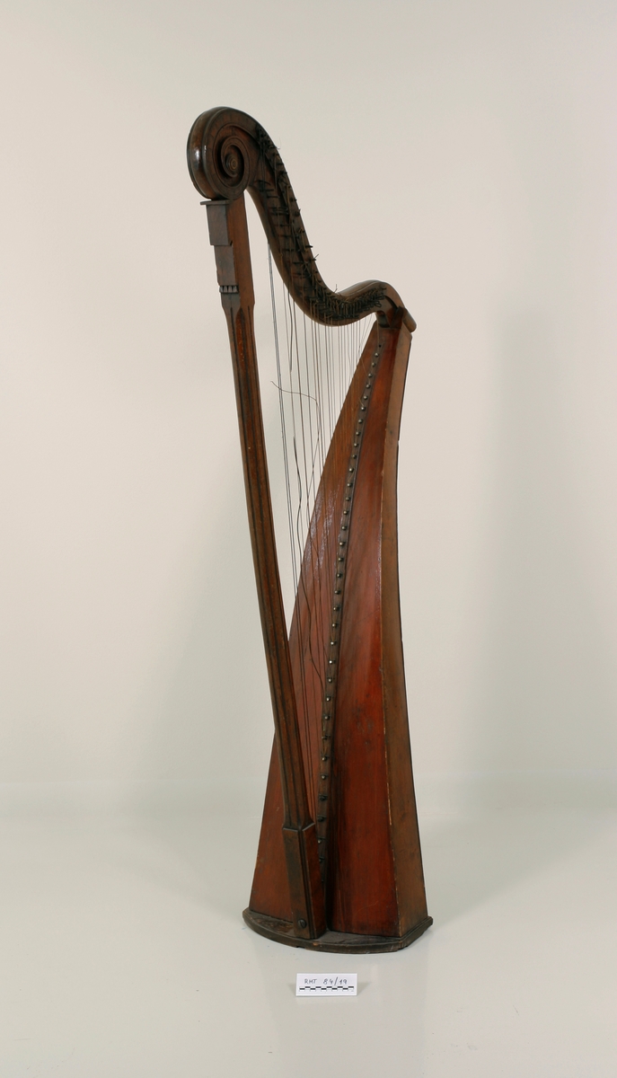 Hakeharpe, med hakemekanikk, i barokk stil. Rett forstang, kannelert søyle og buet kasse. Haker av jern. Innvendig forsterninger under lokket. 35 strenger; strengestol (Bredde, diskant: 15mm, bass: 31mm) dekorert på øvre avslutning. Ingen signatur eller produksjonsnummer.