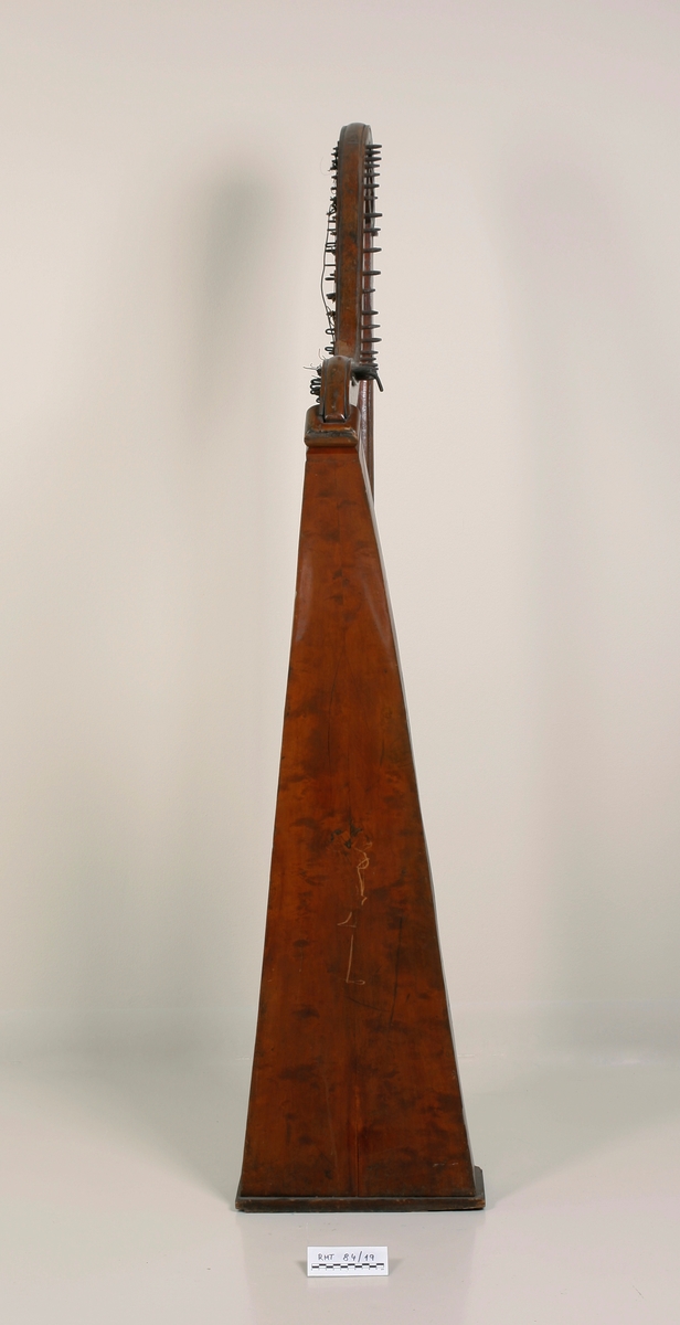 Hakeharpe, med hakemekanikk, i barokk stil. Rett forstang, kannelert søyle og buet kasse. Haker av jern. Innvendig forsterninger under lokket. 35 strenger; strengestol (Bredde, diskant: 15mm, bass: 31mm) dekorert på øvre avslutning. Ingen signatur eller produksjonsnummer.