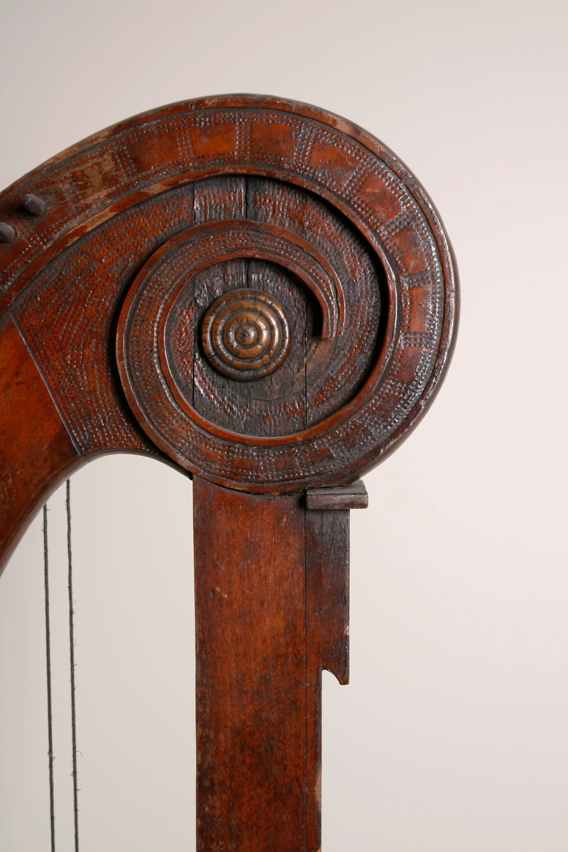Hakeharpe, med hakemekanikk, i barokk stil. Rett forstang, kannelert søyle og buet kasse. Haker av jern. Innvendig forsterninger under lokket. 35 strenger; strengestol (Bredde, diskant: 15mm, bass: 31mm) dekorert på øvre avslutning. Ingen signatur eller produksjonsnummer.