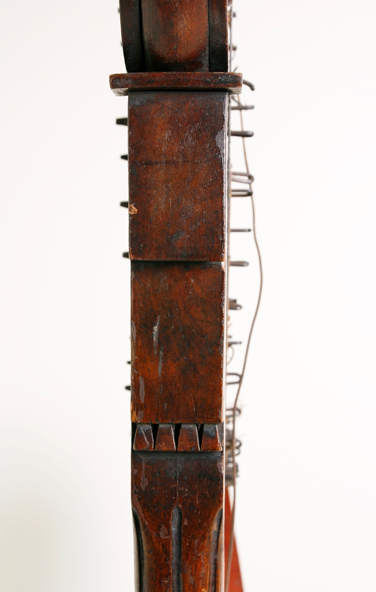 Hakeharpe, med hakemekanikk, i barokk stil. Rett forstang, kannelert søyle og buet kasse. Haker av jern. Innvendig forsterninger under lokket. 35 strenger; strengestol (Bredde, diskant: 15mm, bass: 31mm) dekorert på øvre avslutning. Ingen signatur eller produksjonsnummer.