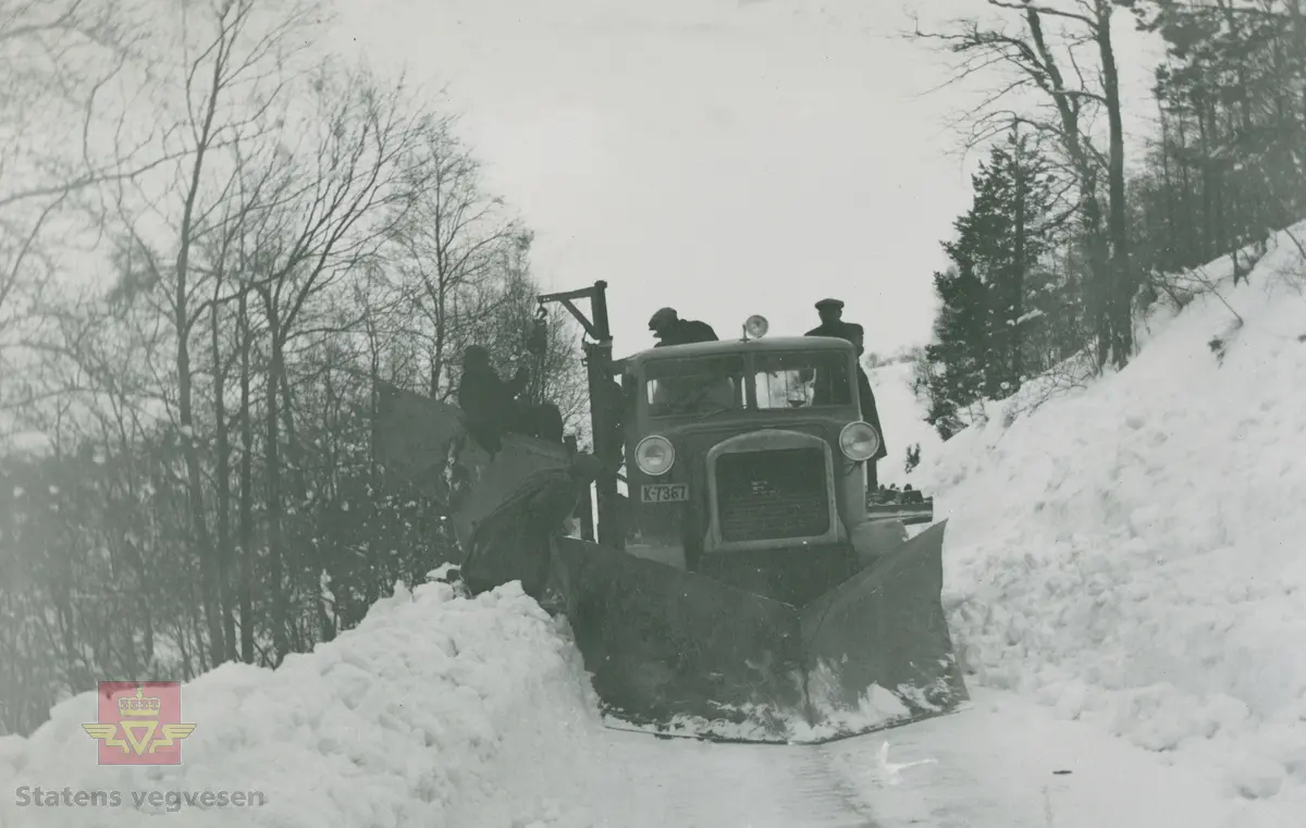FWD lastebil 1936 modell og påmontert sideplog. Kjennetegn K-7367. Ref. til artikkel om snøploger og snøskjermer i  "Vegvesenets redskaper og maskiner 1941," av overingeniør Johs. Eggen. 

25.08.2016: "K-7367 må være registrert ikke lenge etter at redaksjonen for Norges Bilbok 1935 ble avsluttet, sannsynligvis våren det året, siden høyeste nr. i K-7000 serien der er 7319."

30.03.2017: "Bildet er tatt i  Holmelia ved Holmevann 100 meter før en når Sveien høyeste punkt på Kvinesheia. Vegvesenet har besøk av Coldbjørnsen fra Oslo for å se på den påmonterte sideplog på FWD. Bildet er tatt våren 1938."