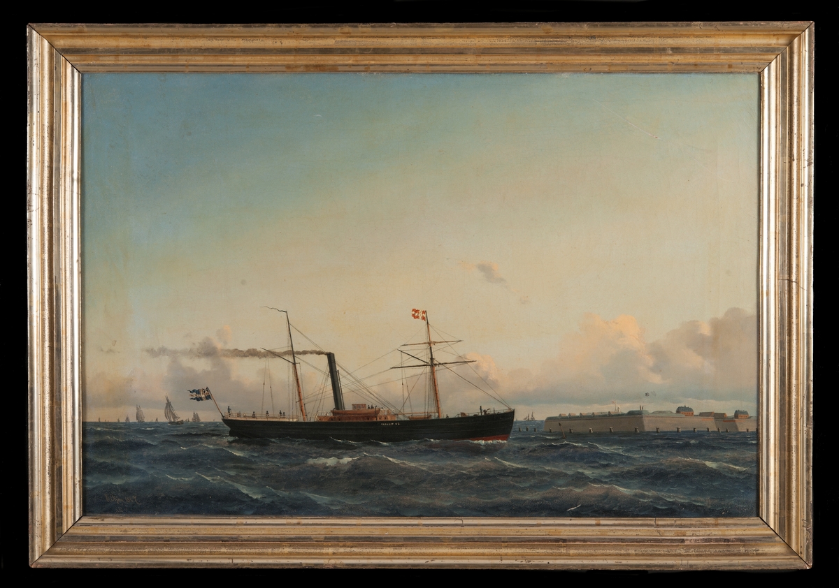 Ångfartyget "Transit N.2"  under gång. Skonertriggat med fastgjorda segel. Svart skrov med röd botten. Dansk flagg på förtoppen. Akter ut svensk flagg med unionsmärke.