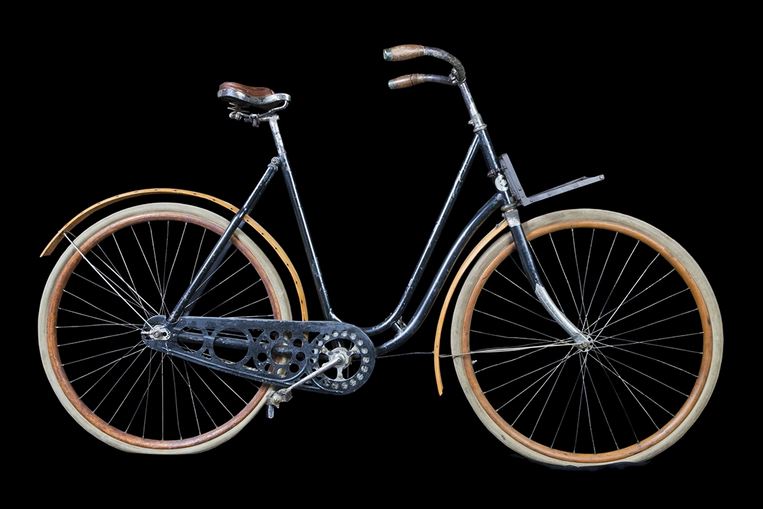 Cykel, dammodell av stålrör. Sadel, läder, i plåtram på spiralfjädrar. Styrstångshandtag av trä. Ringklocka. Pakethållare fäst till styrröret med bultklammer. Träfälgar. Däck av märket TINGVALLA. Suspensionsekrar. Stänkskärmar av trä, den bakre med hål för fästande av kjolnät. Hel vev. Kedja av 2,4 cm långa länksidor, alla med oval mittöppning, förenade genom massiva mellanstycken. Kedjeskydd av plåt genombrutet i cirkelmönster. Svart med förkromat styre. Fälgar och stänkskärmar oljestrukna. På styrrörets framsida korsformig kartusch i vitmetall mellan två nymånar vända mot varandra. Märkning: "N:o 12, CRESCENT, WESTERN WHEEL WORKS, CHICAGO, U.S.A"