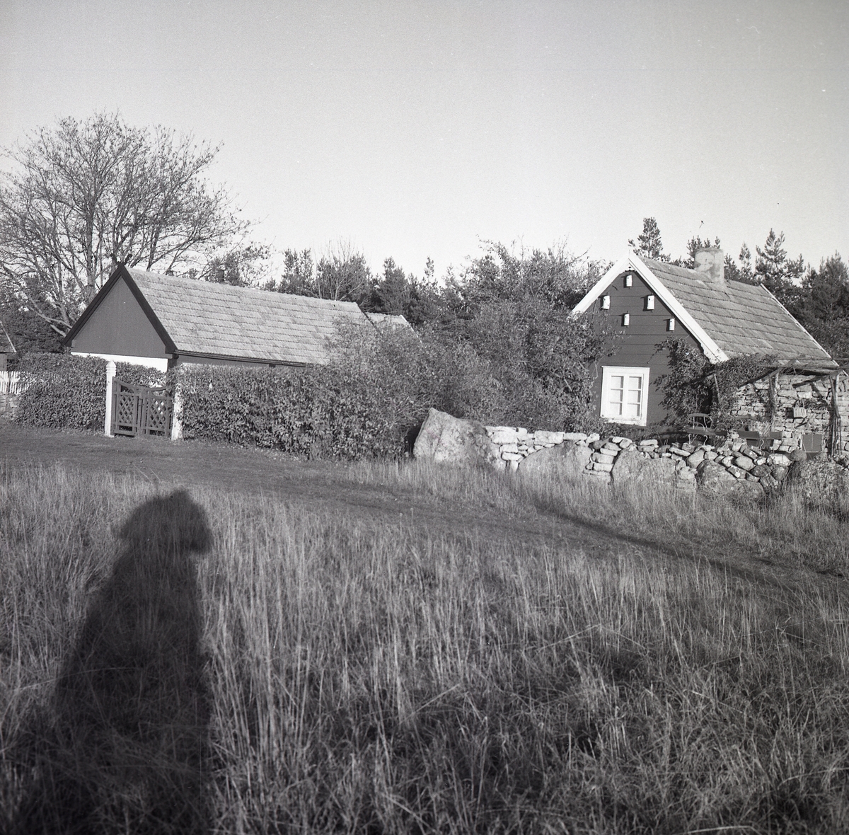 Ett bostadshus och en ekonomibyggnad bakom en stenmur i Lopperstad.