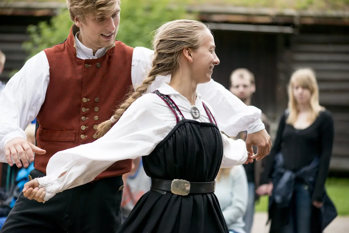 Man og kvinne i folkedrakt danser folkedans