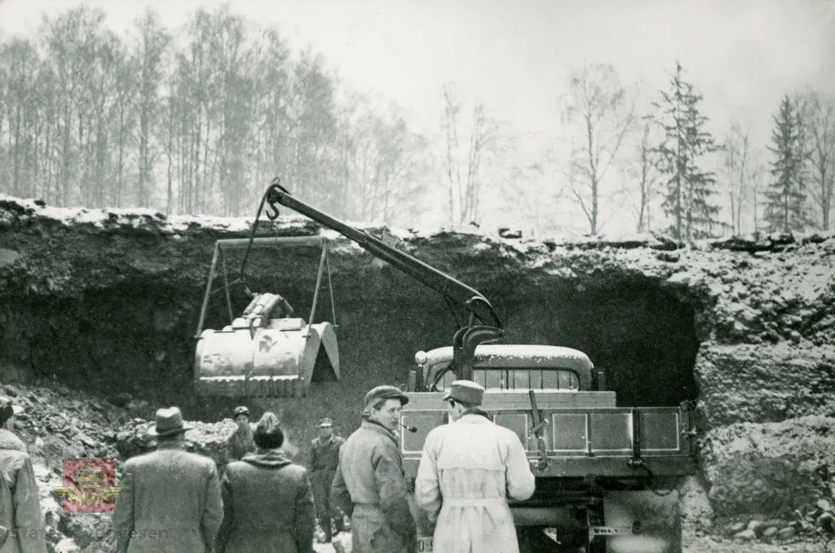 Volvo lastebil og grabb. Knyttes til bilde NVM 00-F-34031. Colbjørnsen med flere beskuer det hele.