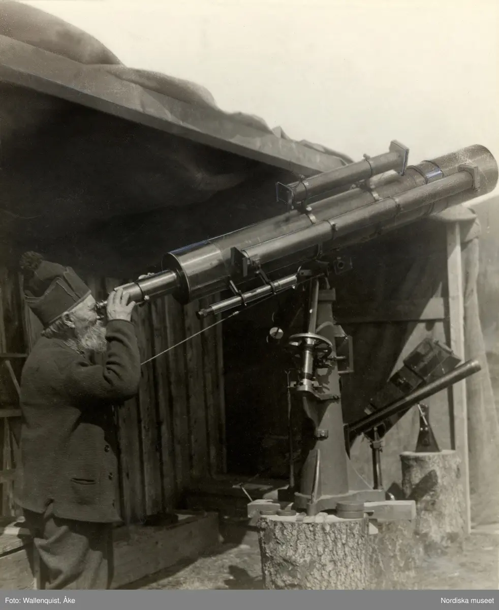 Påskrift: "Solförmörkelseexpeditionen till Ljungdalen 1927. Fjälltopparna beskådas av ortsbefolkningen". En man tittar i eett teleskop mot himlen.