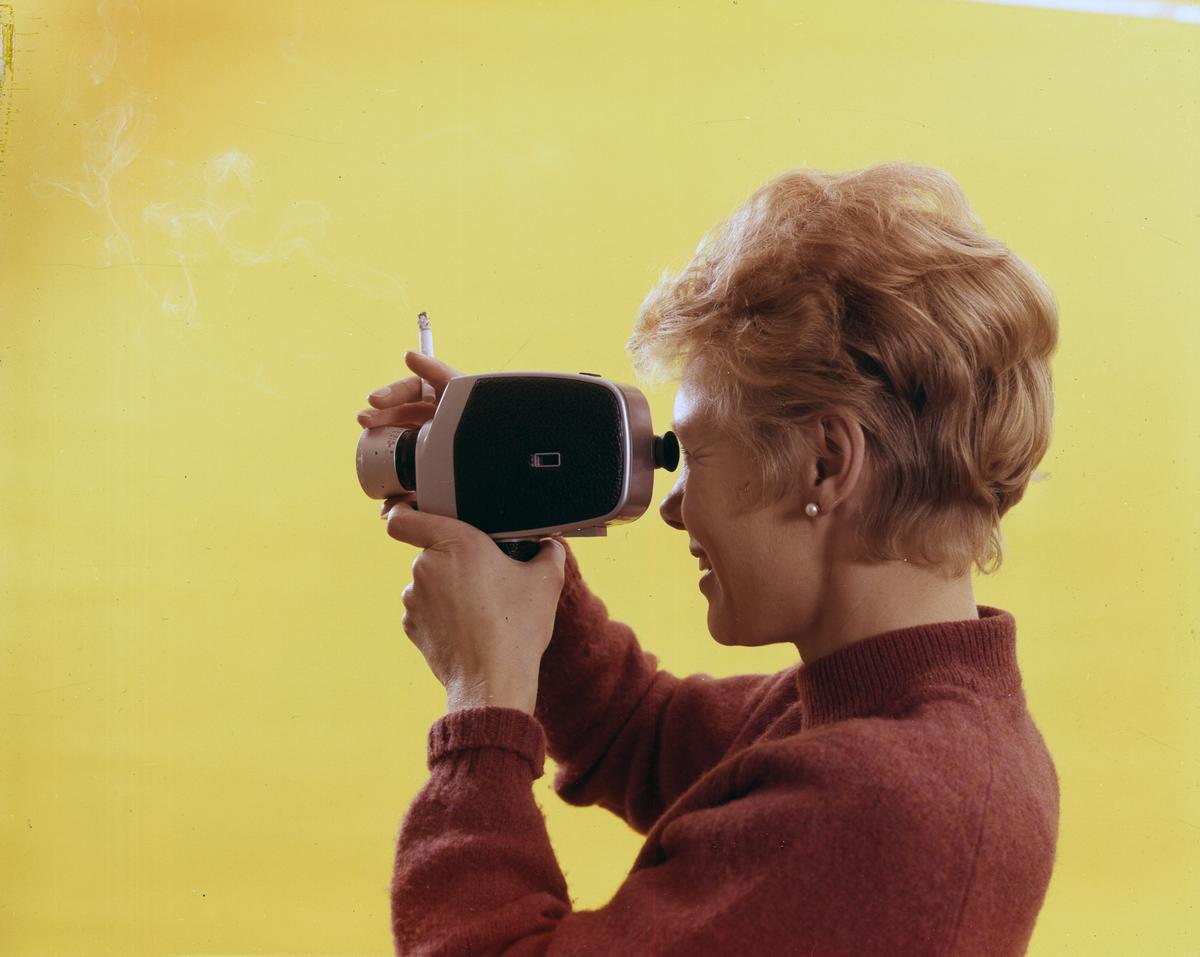 Reklamefoto fra Tiedemanns Tobaksfabrik. Kvinnelig modell med sigarett og filmkamera.