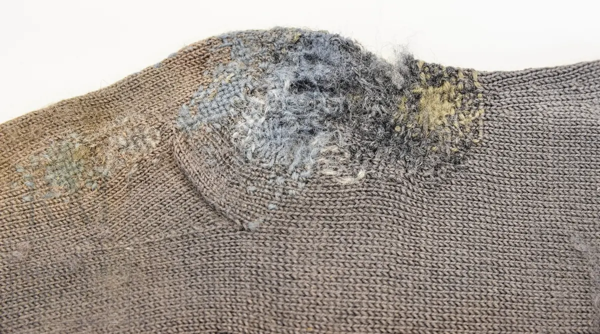 Strømper, 1 par, kvinne. Håndstrikket av ullgarn, grå 8,5cm vrangbord 2r2vr øverst. Kilehel og rund tåfelling. Felling bak på leggen. Innfelt strikket lapp på kneet på B. Hull og stopping. Misfarget føtter.
