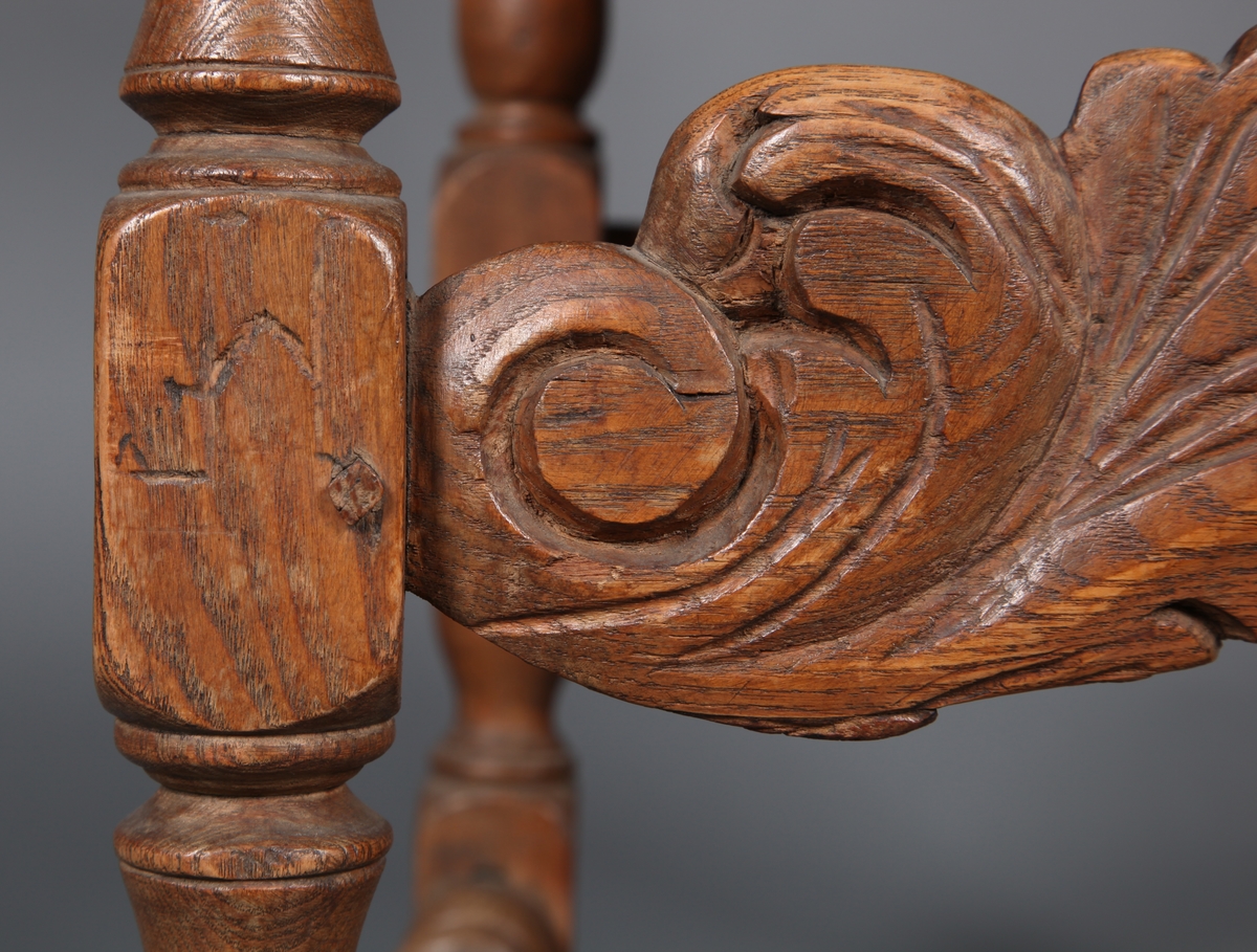 Stol med sete og rygg av lær og med dreiete buete bein. Mellom bein i front er det et utskåret stykke. Rosettformete nagler.