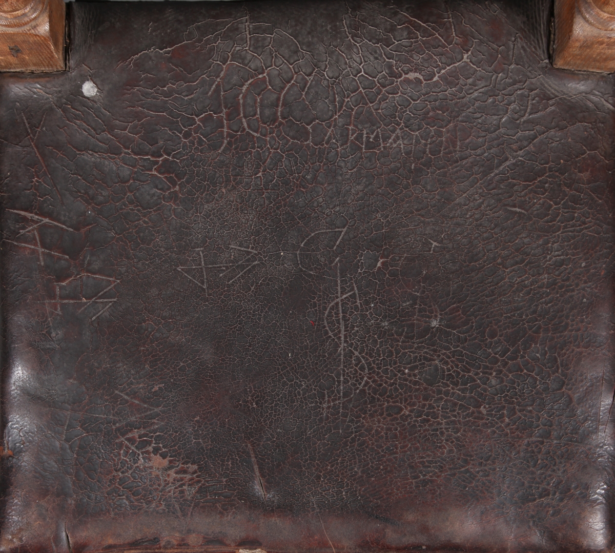 Stol med sete og rygg av lær og med dreiete buete bein. Mellom bein i front er det et utskåret stykke. Rosettformete nagler.