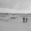 Provflygplan Saab 210 Lilldraken står på flygfältet på F 8 Barkarby. Tre militärer vid flygplanet.