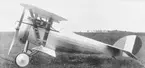 Franskt militärt flygplan Nieuport 27 står på ett flygfält. Vy framifrån och från sidan.