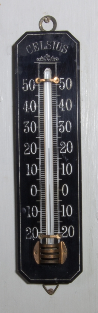 Inomhustermometer av trä, stående rektangulär form med avfasade hörn. Svartmålad med vita siffror från - 20 till + 50. Glasrör med kvicksilverpelare. Glasröret fäst med mässingsbeslag.