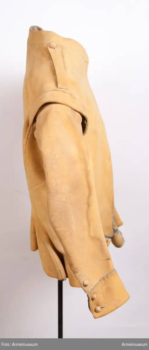 Kyller av gul älghud med smala blå linneband som kantning på insidan samt som passpoal vid övre kant av ärmuppslagen.
Helt framstycke med utsvängt kort skört med uppvik framtill, samt bakstycke med mitt-bak-söm och två sidstycken. Sidsöm under ärmen. Formad tvåsömsärm med ärmuppslag. Ärmuppslagen har sprund som knäpps med 3 koniska älghudsknappar i varje sida, även om det är utskuret 6 knapphål i höger ärm och 5 i den vänstra. De knapphål som inte används är ihopsydda. Liten axelkarm, samt axelklaffar på båda sidor som är fastsydda vid axelsömmen samt knäpps med älghudsknapp vid halsen. Knapp saknas på vänster axel.
Låg ståndkrage som har varit kantad på insidan med blått band. Detta saknas i dag.
Plagget knäpps kant i kant med 12 stycken hyskor och hakar mitt fram. Alla sömmar är sydda med oblekt lintråd.
Märkt inuti ryggen "No 1".
Kyllret skiljer sig något från samtida kyller av samma modell genom att de blå banden är smalare.