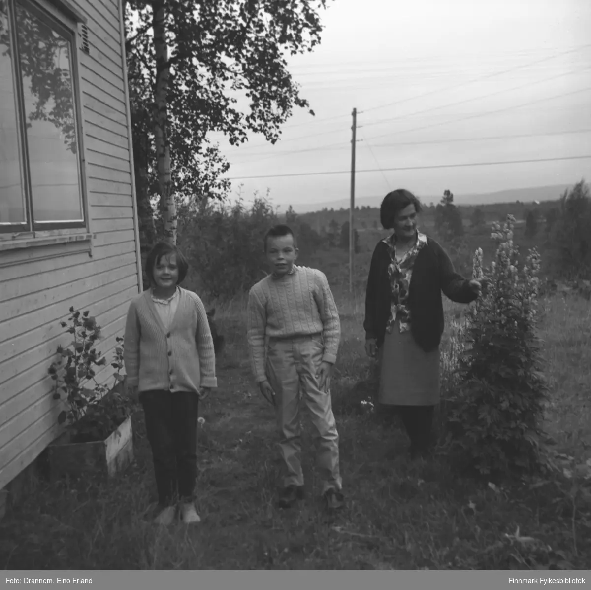 Tre personer utenfor et hus i Pasvik. De er fra venstre: Elin Karikoski, Gunnar Grunnfos og Natalie Karikoski.