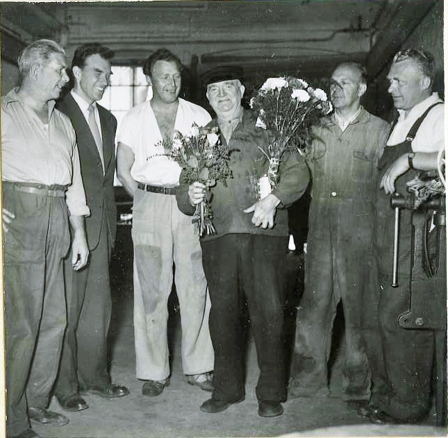 AB Papyrus.  Sven "Sme-Sven"Svensson  uppmärksammas med blomma från kollega. 30/6 1956. Omgiven av fem kollegor.
Okänd, Nils Nilsson, Okänd, Sven Gustaf Svensson, Ossian Forsell och Okänd.