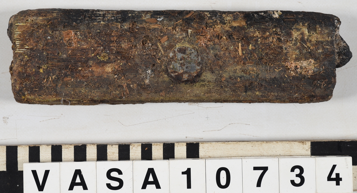 Odekorerad rektangulär bräda med ett spikhål. Tapp på båda ändarna möjlig spont på långsidan. Mycket vittrad yta. Kraftig saltskada (Salt 4) Tapparna avsplittrade.