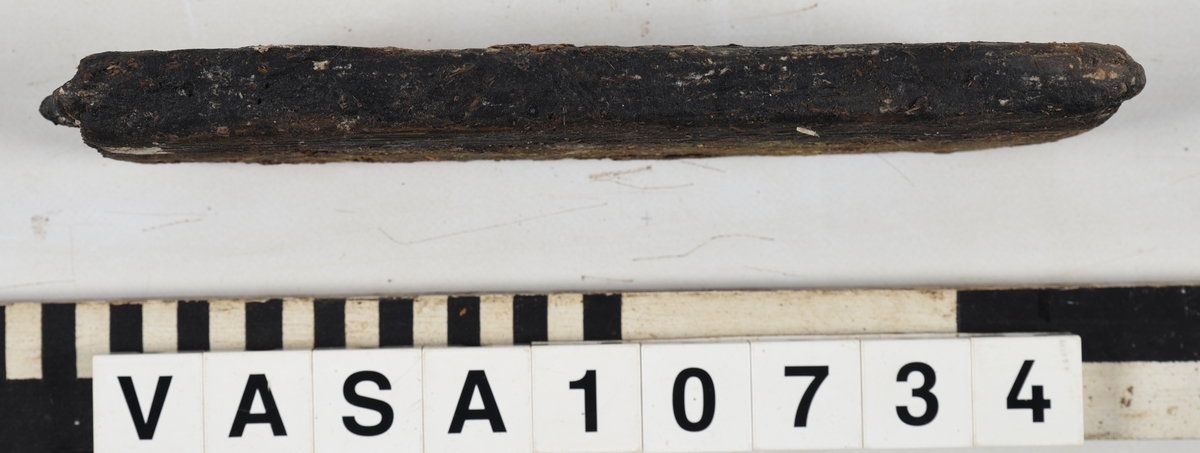 Odekorerad rektangulär bräda med ett spikhål. Tapp på båda ändarna möjlig spont på långsidan. Mycket vittrad yta. Kraftig saltskada (Salt 4) Tapparna avsplittrade.