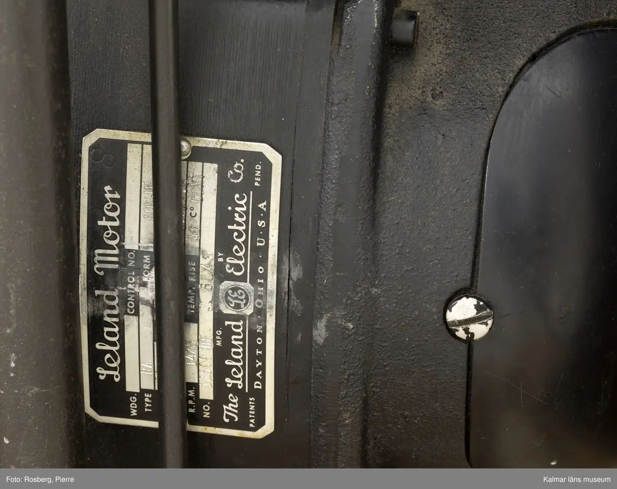 KLM 45739:1. Adresseringsmaskin, präglingsmaskin. Användes för prägling av aluminiumplåtar till registersystem m.m. Maskin av rödlackerad metall och svart plast. På vänstra sidan firmamärke: Citograf. I mitten finns präglingsmaskinen och på vardera sida ett fack för registerplåtar. Till vänster sitter en manuskripthållare. På undersidan sitter en motor av fabrikat Leland Motor, USA, samt en fotpedal. Till maskinen hör en elsladd. Bakom en lucka på baksidan finns instansade siffror och bokstäver: P4822.