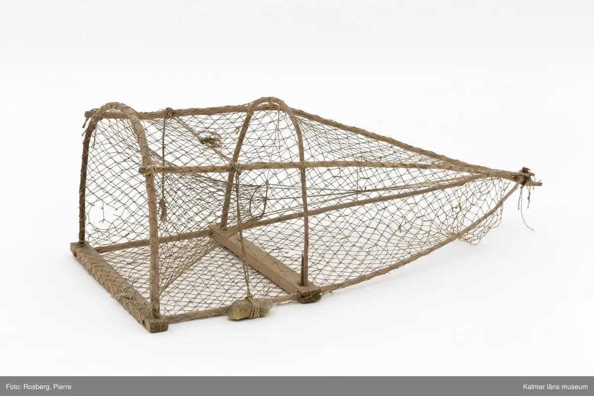 KLM 45862. Mjärde. Avlång fångstbur med stomme av trä och vidjor böjda till bågar med bundet nät av naturmaterial runt om. Även längsgående vidjor som i änden är hopknutna. Inuti en strutformad inredning med en ingång för fisken. På ovansidan två fastbundna rep, i den ena en sten som fungerade som tyngd.