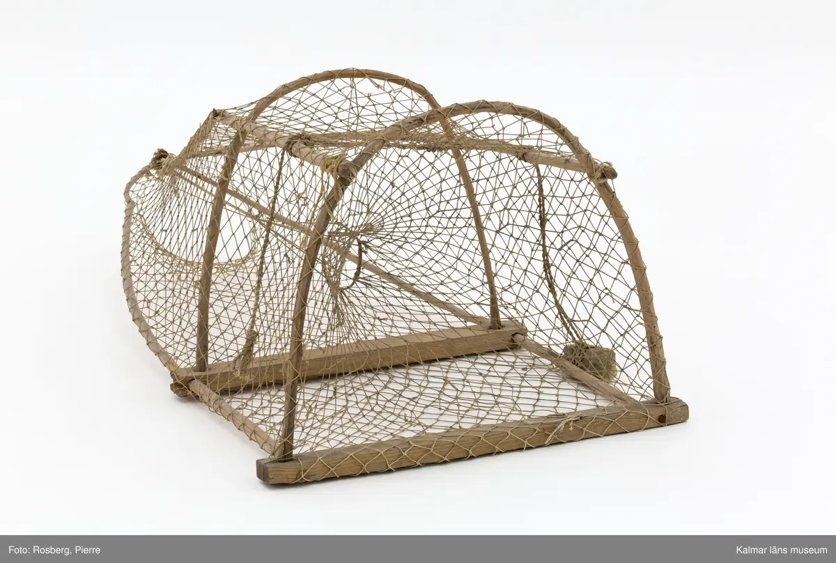 KLM 45862. Mjärde. Avlång fångstbur med stomme av trä och vidjor böjda till bågar med bundet nät av naturmaterial runt om. Även längsgående vidjor som i änden är hopknutna. Inuti en strutformad inredning med en ingång för fisken. På ovansidan två fastbundna rep, i den ena en sten som fungerade som tyngd.