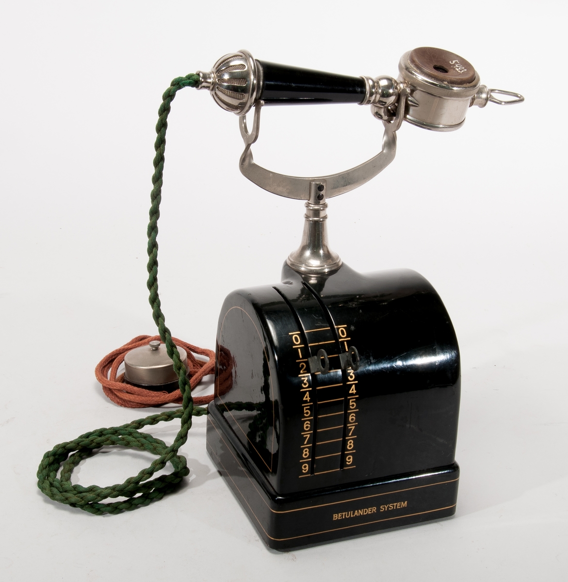 Automatisk med monofon, Betulanderapparat för två siffror, 1913 års

Telefonen fungerar på så sätt att man först ställer in det nummer man vill nå med spakarna. När man lyfter luren sänder ett impulsverk automatiskt numret så att växeln kopplar fram samtalet.