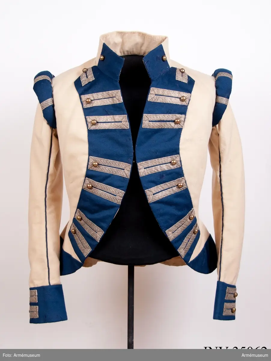 Rekonstruktion av jacka m/1781 för officer vid Lätta livdragonerna.
Jackan är sydd av vitt kläde med kragspeglar, bröstrevärer, axelkarmar och ärmuppvik i mörkblått kläde. Passpoaler av blått kläde i ryggsömmar och främre delsömmar på ärmarna.
Den är dekorerad med metallgaloner på bröstrevärer, axelkarmar och ärmuppslag, och har 16 icke funktionella kulknappar av mässing fram, samt 2 i varje ärmslut och 2 vid ryggslutet bak.
Mitt-fram-linjen är kraftigt svängd, och framstyckena är vadderade över bröstet. Jackan stängs mitt fram samt i ärmsprunden med hysk och hake. 
Den är konstruerad med avskärning i midjan, samt insnitt fram. Separata sidstycken. Skört utan slits bak.
Axelkarmarna är vadderade och står rakt upp.
Jackan är helfodrad med vitt bomullstyg.

Plaggets skärning och sömmar, de vadderade axeltungorna, de djupt skurna bröstrevärerna, uppviken, fodret m.m. indikerar ganska tydligt att den är tillverkad senare, troligen under sent 1800-tal. Även tygkvalitéerna indikerar en yngre datering.