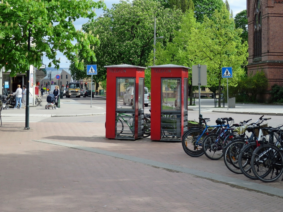 This is the story of how Norway’s most important conversation-space was designed by a young, freshly graduated man from Bergen.

“Norwegian architects are hereby invited…”
In the autumn of 1932, Oslo Telefonanlegginitiated an architectural competition. Finally, Oslo would get its own telephone booth. The city had had so called “talking-stations” from 1885, which in turn were overtaken by automatic telephones 
 only available at selected Narvesen kiosks. The state 
was of the opinion that now was the time to offer the public a better service; public telephone booths open 24/7, like the ones they already had in Sweden and England. But what would they look like, these new telephone booths? What considerations would it
 be necessary to take when designing it? The telegraph board developed a detailed list of demands and restraints: “The booth is intended to be placed outside on the streets and squares and need to be designed so that snow and ice does not hinder the opening and closing of the doors,” they wrote. “To prevent vandalism, theft, uncleanliness etc. inside the booth, it needs to be designed so that from all angles one may see what is going on in there.” Additionally, it would need to withstand storms and bad weather, and “preferably also being whipped by rain mixed with seawater” 

This was not all: The appearance would have to be «pleasing». The booth also needed to be movable, so that it could be taken in to be serviced at Telegrafverket’s main workshops. The reqired material was iron, and the surface was to be spray painted  preferably using car-body paint. There was a requirement for “a writing shelf, a pack shelf, and a suitable place for the telephone catalogue.” Also, there would need to be an illuminated TELEFON  sign, easily visible from all four angles. The total cost for each booth should not exceed 1000 kroner. The first prize for coming up with such a product was 800 kroner.

“Norwegianarchitects are hereby invited to partake in a competition for the design of a telephone booth…”  

The man with the solution
«At some point in 1932, Georg Fredrik sat at a party in Bergen. Maybe he felt a bit lost and forgotten as he often had throughout his life. He retreated to a quiet corner, took out a pencil and strted doodling on a matchbox.  According to my mother, this was how the telephone booth came into being.” In the book “Norges lille røde  historien om telefonkiosken,” Lars Fasting describes his father, the man who is far less known than the iconic architctural structure he left behind. Georg Fredrik Fasting was from Bergen, born into a family of working people and smallholders. One unusual facet of Georg Fredrik was that he was born without ears. His mother made sure he learnt to speak, read and write, 
ut Lars Fasting indicates that his father would seek refuge in drawing when the social challenges became too much to bear. And in the end drawing became his profession. In 1924 he secured a guarantor for a student loan, and started studying to become an a
rchitect at the NTH. Throughout the 1930s he entered several architectural competitions, with drafts produced, according to his son, “after work and in the late hours of the night.”

His efforts were not wasted. Out of 93 entries, with names such as “Flirt”, “Brrr”, “Ring” and “Amor”, the jury selected Fasting’s submission, “RIKS” as the new telephone booth: “The draft shows a strikingly simple solution to the task, technically as well as aesthetically well worked out.”

Taut and provident
Simple and aesthetc are the keywords here. Fasting had designed a booth pointing towards the future, and to modernism. Just how modern it was can be seen by comparing RIKS to the British telephone booth, also designed in the interwar-era. While the British version with it classicistic style is looking back to the heyday of the empire, Fasting’s booth is progressive and functionalistic. Like most Norwegian architects, Fasting broke with the classicistic style of architecture after the Stockholm-exhibition in 1930. “After it, almost all buildings erected in Norway until the German invasion in 1940, were in the functionalistic architectural style,” writes senior curator of architecture at the Norwegian National Museum, Ulf Grønvold, in the book, “Den lille røde”.“TheNorwegian booth is a piece of functionalistic architecture, an asymmetric composition with its roof slab overhanging the word TELEFON, in bold sans seraph lettering,”concludes Ulf Grønvold.

Fashionably red
And it was red. Fasting chose a colour which was part of the modern palette. “A bright red colour, but not as shiny as a signal red, the character of the colour places it among the fashionable colours within functionalism,” states paintings conservator and researcher in NIKU (Norwegian Institute for Cultural Heitage Research), Jon Brænne. In his opinion, Fasting went for visibility without making the booth stand out too much from its surroundings. The original colour was in use up to around 1950, when it changed to signal red. Towards the end of the 1970s the clour was again adjusted towards today’s orangey red.

The design, however, has not changed. RIKS is eighty years and still looks remarkably good. That’s what makes Fasting’s telephone booth a classic  even before it was added to DOCOMOMO’s list over moden icons of design. For Telenor, the telephone booth has served as a pathway into the hearts of the public. For many, Telenor (Televerket) was synonymous with exactly this telephone booth, because this was where one would go to place a call. Having a home
phone was not common until the 1980s. As such the red box became part of the Norwegian everyday and consciousness. The symbol- and publicity value of this is hard to evaluate, but in 2007 it was time to give honour where honour was due, Telenor, in consul
tation with the Directorate for Cultural Heritage, decided to preserve 100 telephone booths for all eternity.

And what about Georg Fredrik Fasting? What happened to him? At the age of 56 an entry in his diary states: «I CAN HEAR». As the first person in th world he had undergone an operation where he had ear canals constructed and eardrums fitted. For the rest of his life, the man behind Norway’s own telephone booth could answer the telephone himself.

Source: Norges lille røde historien om telefonkiosken (2007), issued by The Norwegian Telecom Museum and Telenor Cultural Heritage.