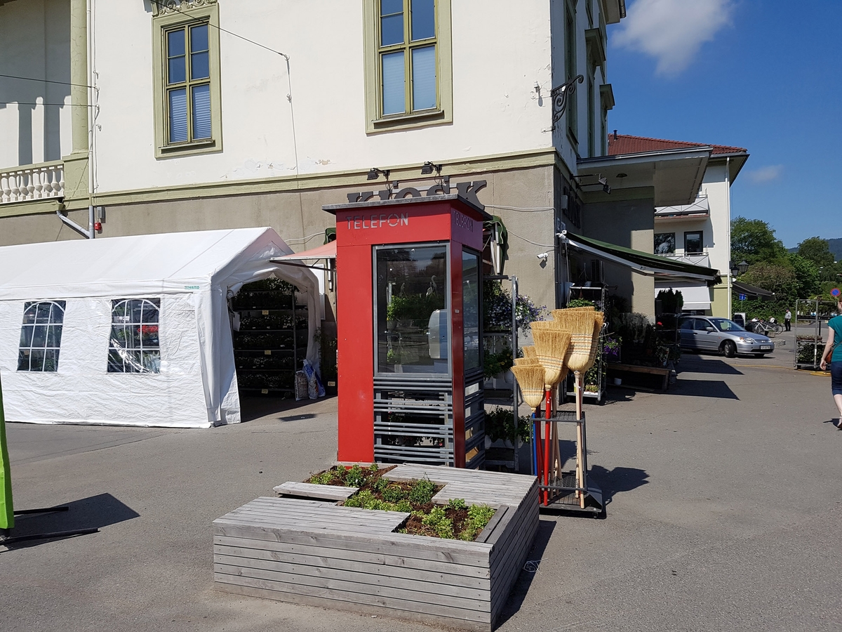 This is the story of how Norway’s most important conversation-space was designed by a young, freshly graduated man from Bergen.

“Norwegian architects are hereby invited…”
In the autumn of 1932, Oslo Telefonanlegginitiated an architectural competition. Finally, Oslo would get its own telephone booth. The city had had so called “talking-stations” from 1885, which in turn were overtaken by automatic telephones 
 only available at selected Narvesen kiosks. The state 
was of the opinion that now was the time to offer the public a better service; public telephone booths open 24/7, like the ones they already had in Sweden and England. But what would they look like, these new telephone booths? What considerations would it
 be necessary to take when designing it? The telegraph board developed a detailed list of demands and restraints: “The booth is intended to be placed outside on the streets and squares and need to be designed so that snow and ice does not hinder the opening and closing of the doors,” they wrote. “To prevent vandalism, theft, uncleanliness etc. inside the booth, it needs to be designed so that from all angles one may see what is going on in there.” Additionally, it would need to withstand storms and bad weather, and “preferably also being whipped by rain mixed with seawater” 

This was not all: The appearance would have to be «pleasing». The booth also needed to be movable, so that it could be taken in to be serviced at Telegrafverket’s main workshops. The reqired material was iron, and the surface was to be spray painted  preferably using car-body paint. There was a requirement for “a writing shelf, a pack shelf, and a suitable place for the telephone catalogue.” Also, there would need to be an illuminated TELEFON  sign, easily visible from all four angles. The total cost for each booth should not exceed 1000 kroner. The first prize for coming up with such a product was 800 kroner.

“Norwegianarchitects are hereby invited to partake in a competition for the design of a telephone booth…”  

The man with the solution
«At some point in 1932, Georg Fredrik sat at a party in Bergen. Maybe he felt a bit lost and forgotten as he often had throughout his life. He retreated to a quiet corner, took out a pencil and strted doodling on a matchbox.  According to my mother, this was how the telephone booth came into being.” In the book “Norges lille røde  historien om telefonkiosken,” Lars Fasting describes his father, the man who is far less known than the iconic architctural structure he left behind. Georg Fredrik Fasting was from Bergen, born into a family of working people and smallholders. One unusual facet of Georg Fredrik was that he was born without ears. His mother made sure he learnt to speak, read and write, 
ut Lars Fasting indicates that his father would seek refuge in drawing when the social challenges became too much to bear. And in the end drawing became his profession. In 1924 he secured a guarantor for a student loan, and started studying to become an a
rchitect at the NTH. Throughout the 1930s he entered several architectural competitions, with drafts produced, according to his son, “after work and in the late hours of the night.”

His efforts were not wasted. Out of 93 entries, with names such as “Flirt”, “Brrr”, “Ring” and “Amor”, the jury selected Fasting’s submission, “RIKS” as the new telephone booth: “The draft shows a strikingly simple solution to the task, technically as well as aesthetically well worked out.”

Taut and provident
Simple and aesthetc are the keywords here. Fasting had designed a booth pointing towards the future, and to modernism. Just how modern it was can be seen by comparing RIKS to the British telephone booth, also designed in the interwar-era. While the British version with it classicistic style is looking back to the heyday of the empire, Fasting’s booth is progressive and functionalistic. Like most Norwegian architects, Fasting broke with the classicistic style of architecture after the Stockholm-exhibition in 1930. “After it, almost all buildings erected in Norway until the German invasion in 1940, were in the functionalistic architectural style,” writes senior curator of architecture at the Norwegian National Museum, Ulf Grønvold, in the book, “Den lille røde”.“TheNorwegian booth is a piece of functionalistic architecture, an asymmetric composition with its roof slab overhanging the word TELEFON, in bold sans seraph lettering,”concludes Ulf Grønvold.

Fashionably red
And it was red. Fasting chose a colour which was part of the modern palette. “A bright red colour, but not as shiny as a signal red, the character of the colour places it among the fashionable colours within functionalism,” states paintings conservator and researcher in NIKU (Norwegian Institute for Cultural Heitage Research), Jon Brænne. In his opinion, Fasting went for visibility without making the booth stand out too much from its surroundings. The original colour was in use up to around 1950, when it changed to signal red. Towards the end of the 1970s the clour was again adjusted towards today’s orangey red.

The design, however, has not changed. RIKS is eighty years and still looks remarkably good. That’s what makes Fasting’s telephone booth a classic  even before it was added to DOCOMOMO’s list over moden icons of design. For Telenor, the telephone booth has served as a pathway into the hearts of the public. For many, Telenor (Televerket) was synonymous with exactly this telephone booth, because this was where one would go to place a call. Having a home
phone was not common until the 1980s. As such the red box became part of the Norwegian everyday and consciousness. The symbol- and publicity value of this is hard to evaluate, but in 2007 it was time to give honour where honour was due, Telenor, in consul
tation with the Directorate for Cultural Heritage, decided to preserve 100 telephone booths for all eternity.

And what about Georg Fredrik Fasting? What happened to him? At the age of 56 an entry in his diary states: «I CAN HEAR». As the first person in th world he had undergone an operation where he had ear canals constructed and eardrums fitted. For the rest of his life, the man behind Norway’s own telephone booth could answer the telephone himself.

Source: Norges lille røde historien om telefonkiosken (2007), issued by The Norwegian Telecom Museum and Telenor Cultural Heritage.