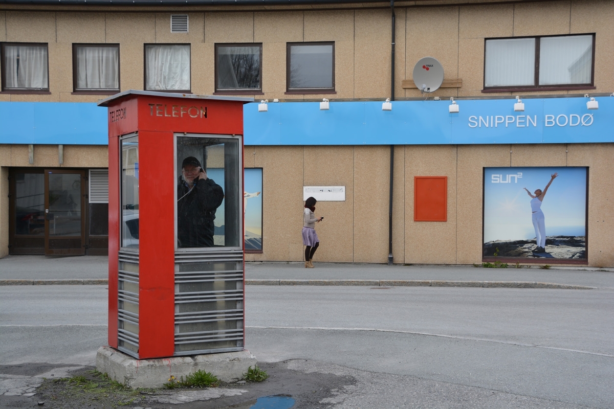 This is the story of how Norway’s most important conversation-space was designed by a young, freshly graduated man from Bergen.

“Norwegian architects are hereby invited…”
In the autumn of 1932, Oslo Telefonanlegginitiated an architectural competition. Finally, Oslo would get its own telephone booth. The city had had so called “talking-stations” from 1885, which in turn were overtaken by automatic telephones 
 only available at selected Narvesen kiosks. The state 
was of the opinion that now was the time to offer the public a better service; public telephone booths open 24/7, like the ones they already had in Sweden and England. But what would they look like, these new telephone booths? What considerations would it
 be necessary to take when designing it? The telegraph board developed a detailed list of demands and restraints: “The booth is intended to be placed outside on the streets and squares and need to be designed so that snow and ice does not hinder the opening and closing of the doors,” they wrote. “To prevent vandalism, theft, uncleanliness etc. inside the booth, it needs to be designed so that from all angles one may see what is going on in there.” Additionally, it would need to withstand storms and bad weather, and “preferably also being whipped by rain mixed with seawater” 

This was not all: The appearance would have to be «pleasing». The booth also needed to be movable, so that it could be taken in to be serviced at Telegrafverket’s main workshops. The reqired material was iron, and the surface was to be spray painted  preferably using car-body paint. There was a requirement for “a writing shelf, a pack shelf, and a suitable place for the telephone catalogue.” Also, there would need to be an illuminated TELEFON  sign, easily visible from all four angles. The total cost for each booth should not exceed 1000 kroner. The first prize for coming up with such a product was 800 kroner.

“Norwegianarchitects are hereby invited to partake in a competition for the design of a telephone booth…”  

The man with the solution
«At some point in 1932, Georg Fredrik sat at a party in Bergen. Maybe he felt a bit lost and forgotten as he often had throughout his life. He retreated to a quiet corner, took out a pencil and strted doodling on a matchbox.  According to my mother, this was how the telephone booth came into being.” In the book “Norges lille røde  historien om telefonkiosken,” Lars Fasting describes his father, the man who is far less known than the iconic architctural structure he left behind. Georg Fredrik Fasting was from Bergen, born into a family of working people and smallholders. One unusual facet of Georg Fredrik was that he was born without ears. His mother made sure he learnt to speak, read and write, 
ut Lars Fasting indicates that his father would seek refuge in drawing when the social challenges became too much to bear. And in the end drawing became his profession. In 1924 he secured a guarantor for a student loan, and started studying to become an a
rchitect at the NTH. Throughout the 1930s he entered several architectural competitions, with drafts produced, according to his son, “after work and in the late hours of the night.”

His efforts were not wasted. Out of 93 entries, with names such as “Flirt”, “Brrr”, “Ring” and “Amor”, the jury selected Fasting’s submission, “RIKS” as the new telephone booth: “The draft shows a strikingly simple solution to the task, technically as well as aesthetically well worked out.”

Taut and provident
Simple and aesthetc are the keywords here. Fasting had designed a booth pointing towards the future, and to modernism. Just how modern it was can be seen by comparing RIKS to the British telephone booth, also designed in the interwar-era. While the British version with it classicistic style is looking back to the heyday of the empire, Fasting’s booth is progressive and functionalistic. Like most Norwegian architects, Fasting broke with the classicistic style of architecture after the Stockholm-exhibition in 1930. “After it, almost all buildings erected in Norway until the German invasion in 1940, were in the functionalistic architectural style,” writes senior curator of architecture at the Norwegian National Museum, Ulf Grønvold, in the book, “Den lille røde”.“TheNorwegian booth is a piece of functionalistic architecture, an asymmetric composition with its roof slab overhanging the word TELEFON, in bold sans seraph lettering,”concludes Ulf Grønvold.

Fashionably red
And it was red. Fasting chose a colour which was part of the modern palette. “A bright red colour, but not as shiny as a signal red, the character of the colour places it among the fashionable colours within functionalism,” states paintings conservator and researcher in NIKU (Norwegian Institute for Cultural Heitage Research), Jon Brænne. In his opinion, Fasting went for visibility without making the booth stand out too much from its surroundings. The original colour was in use up to around 1950, when it changed to signal red. Towards the end of the 1970s the clour was again adjusted towards today’s orangey red.

The design, however, has not changed. RIKS is eighty years and still looks remarkably good. That’s what makes Fasting’s telephone booth a classic  even before it was added to DOCOMOMO’s list over moden icons of design. For Telenor, the telephone booth has served as a pathway into the hearts of the public. For many, Telenor (Televerket) was synonymous with exactly this telephone booth, because this was where one would go to place a call. Having a home
phone was not common until the 1980s. As such the red box became part of the Norwegian everyday and consciousness. The symbol- and publicity value of this is hard to evaluate, but in 2007 it was time to give honour where honour was due, Telenor, in consul
tation with the Directorate for Cultural Heritage, decided to preserve 100 telephone booths for all eternity.

And what about Georg Fredrik Fasting? What happened to him? At the age of 56 an entry in his diary states: «I CAN HEAR». As the first person in th world he had undergone an operation where he had ear canals constructed and eardrums fitted. For the rest of his life, the man behind Norway’s own telephone booth could answer the telephone himself.

Source: Norges lille røde historien om telefonkiosken (2007), issued by The Norwegian Telecom Museum and Telenor Cultural Heritage.